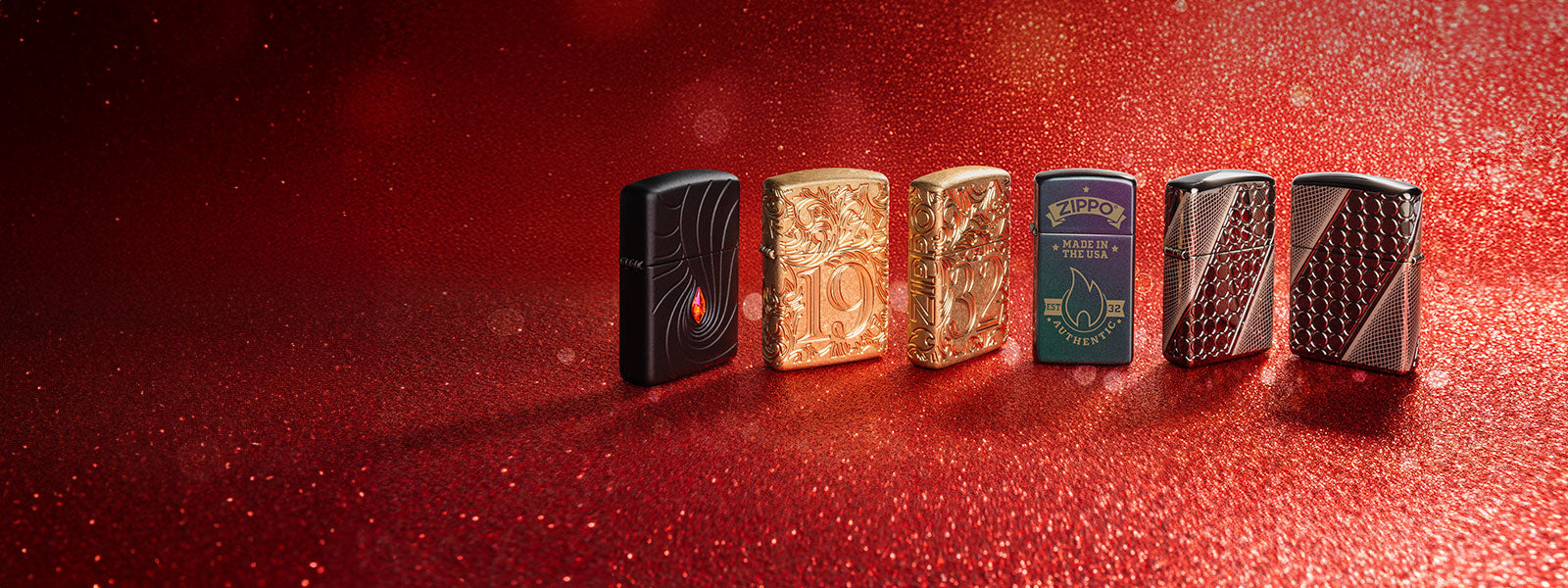 Six metallic lighters arranged in a row on a red textured surface