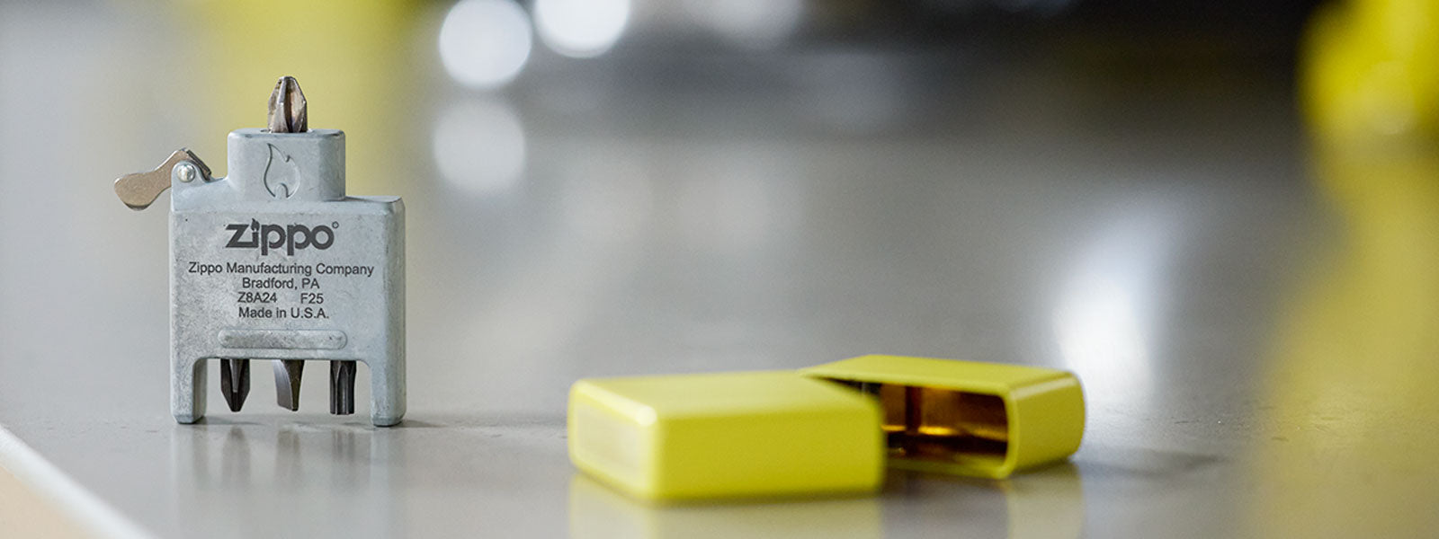 Zippo Bit Safe Screwdriver and yellow lighter case on a reflective surface