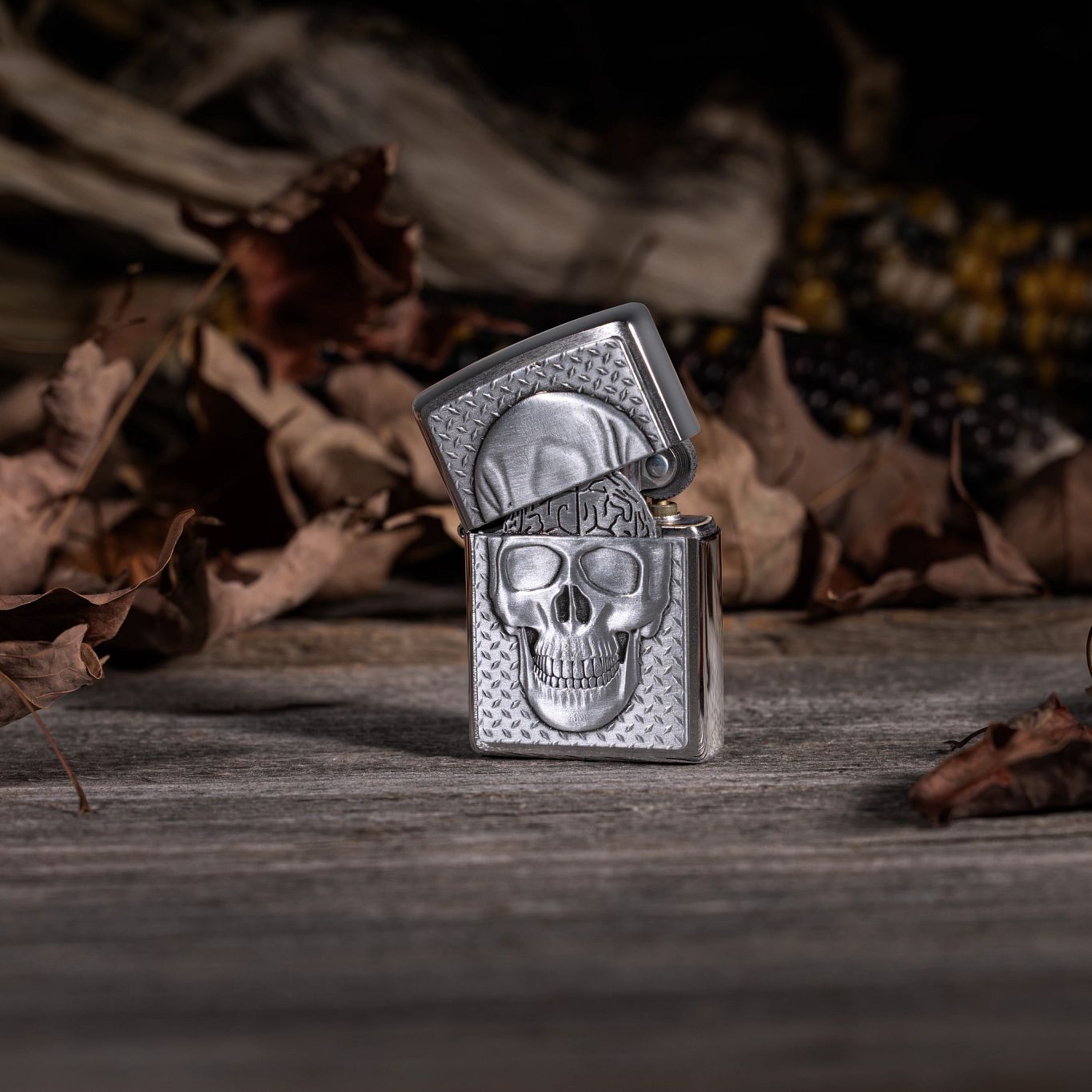 Lifestyle image of Skull with Brain Surprise Windproof Lighter standing on a wooden surface with brown leaves and corn in the background.