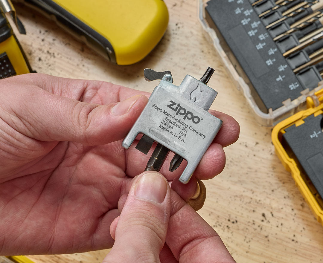 Zippo Bit Safe Insert held by a hand with tools in the background