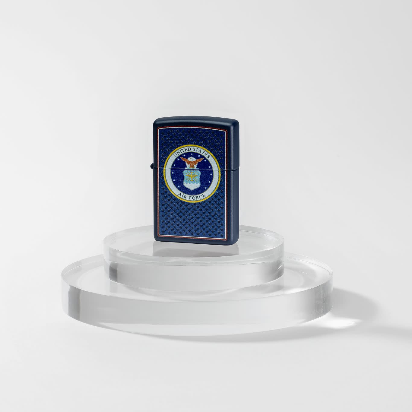 Lifestyle image of Zippo U.S. Air Forceâ„¢ Navy Matte Windproof Lighter standing on a clear two-tier pedestal.