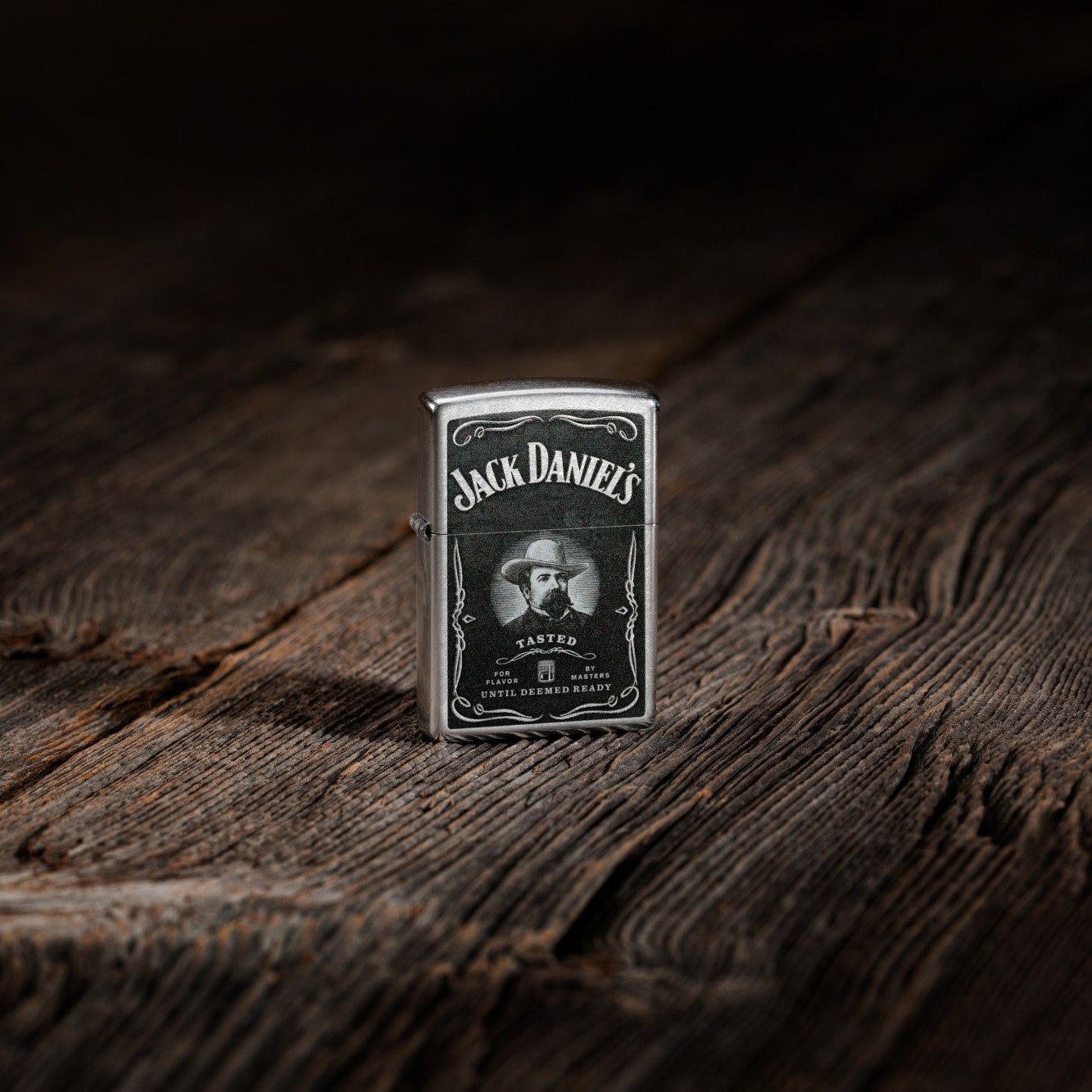 Lifestyle image of Zippo Jack Daniels Street Chrome Windproof Lighter standing on a wooden table.
