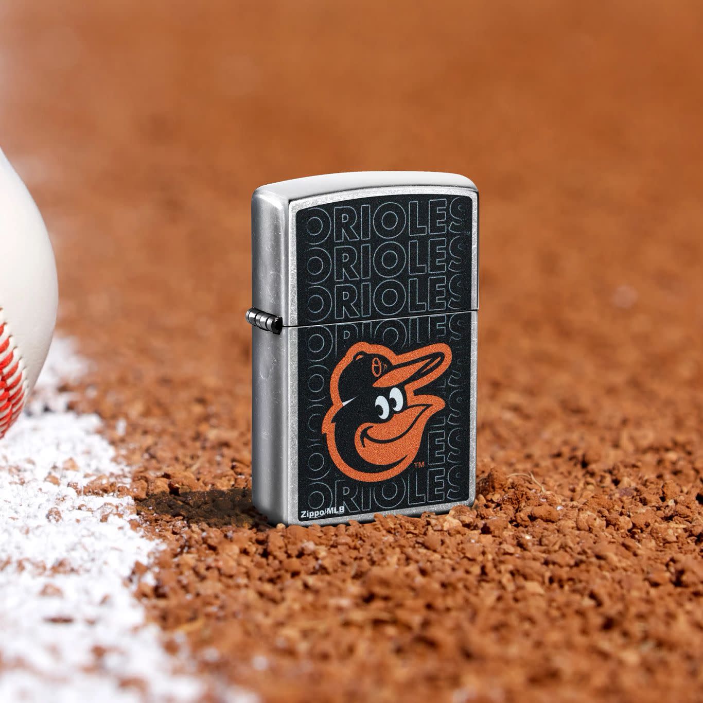 Lifestyle image of Zippo MLB® Baltimore Orioles Street Chrome Windproof Lighter standing in the dirt on a baseball field.