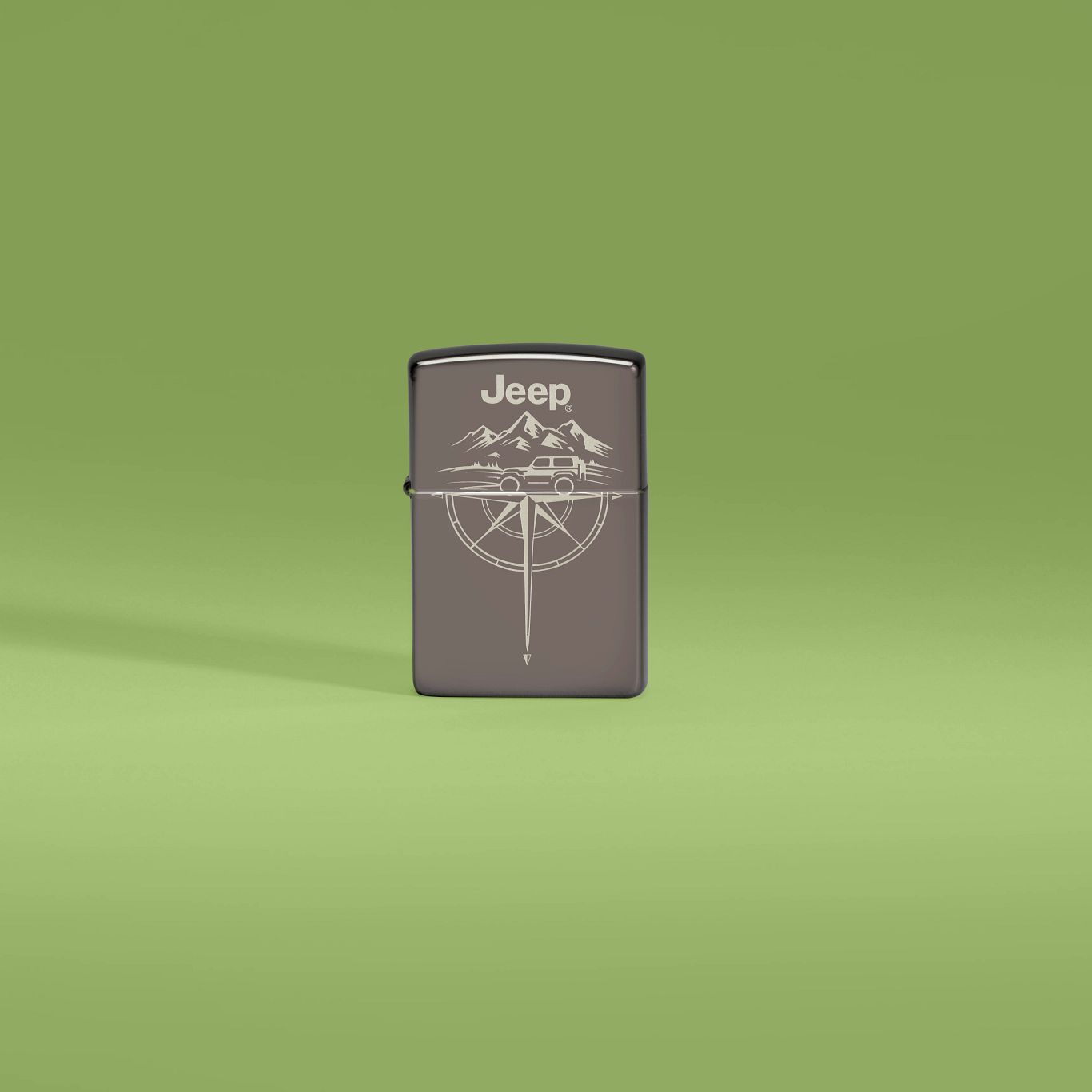 Lifestyle image of Zippo Jeep® Wilderness Design Black Ice Windproof Lighter standing against a green background.