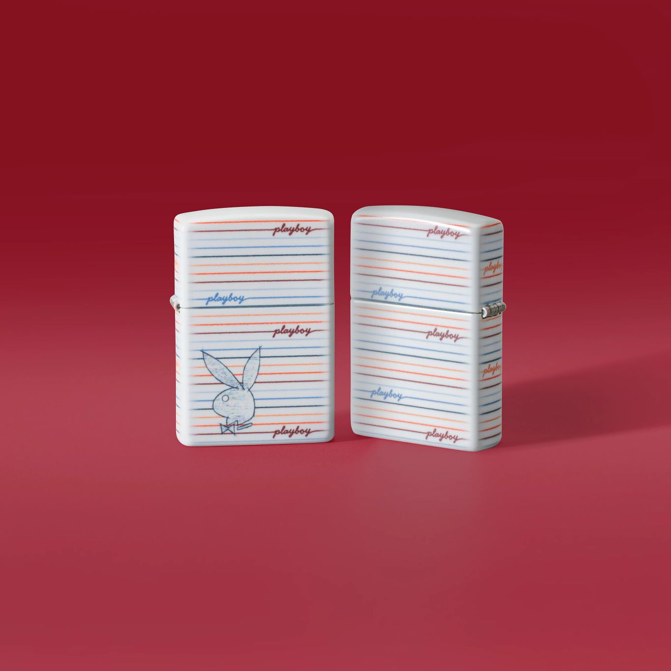 Lifestyle image of two Zippo Playboy Rabbit Silhouette Line Design White 540 Matte Windproof Lighters, one showing the front of the lighter and the other showing the back, standing on a light red background.