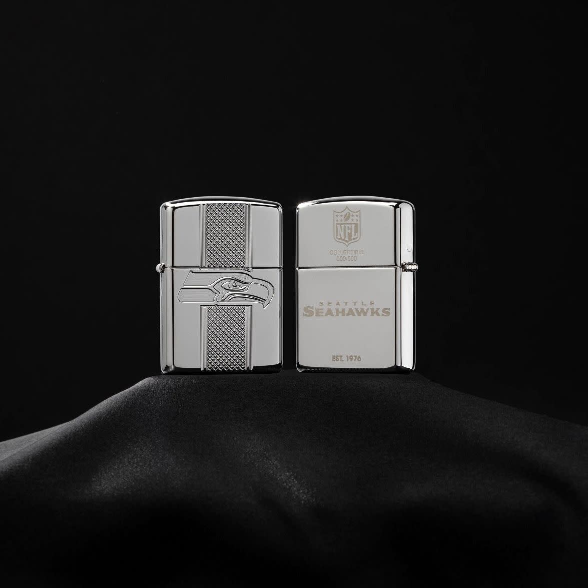 Lifestyle image of NFL Seattle Seahawks Deep Carve Collectible Windproof Lighter standing on a black velvet background showing the front and the back
