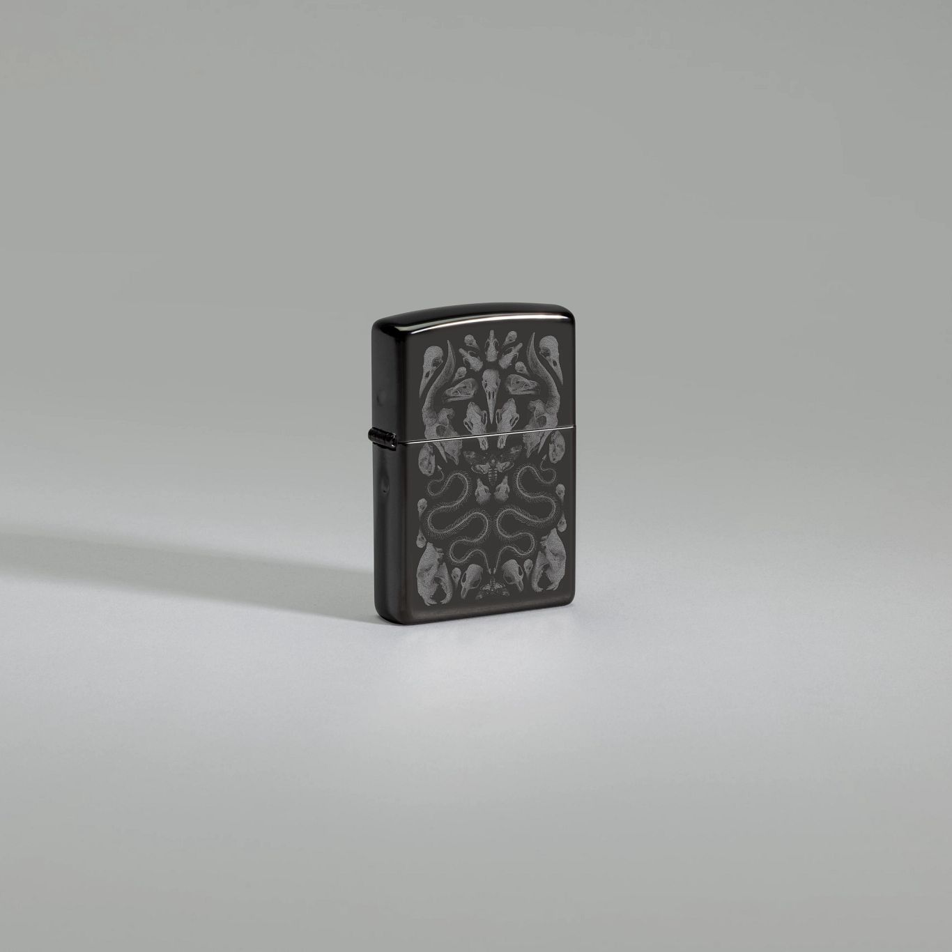 Lifestyle image of Zippo Bone Mosaic Design Ebony Windproof Lighter standing against a light gray background.
