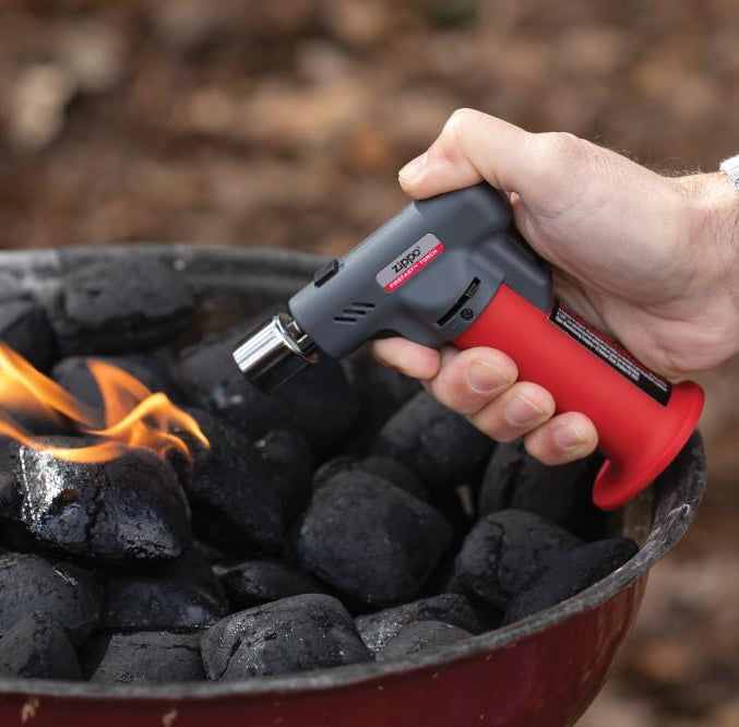 Lifestyle image of Firefast® Torch lighting a charcoal grill.