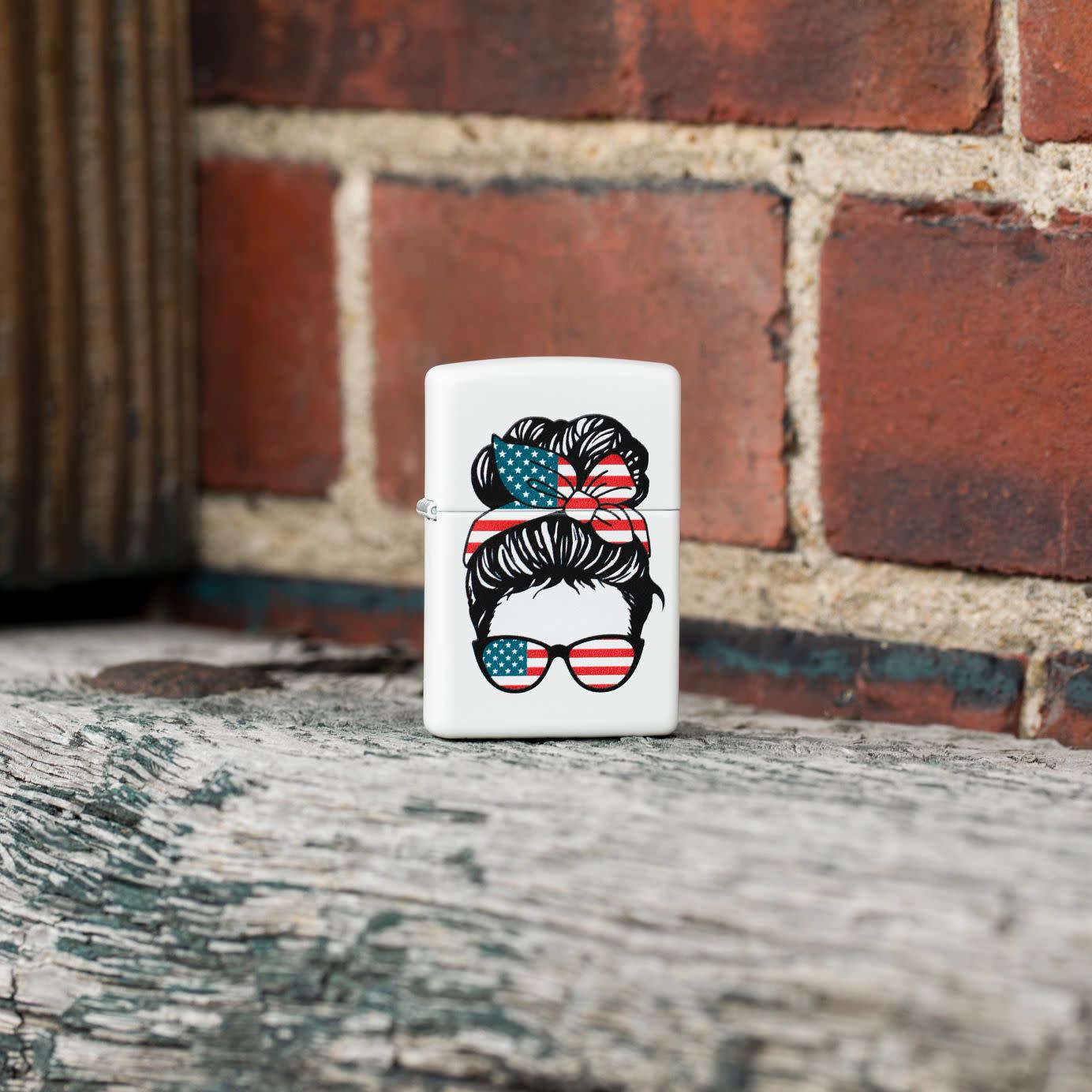 Lifestyle image of Zippo American Woman Design White Matte Windproof Lighter standing in front of a brick wall.
