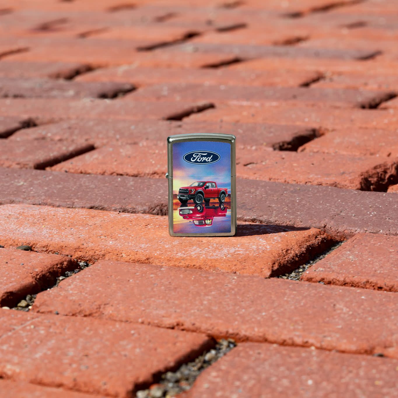 Lifestyle image of Zippo Ford F-Series Design Street Chrome Windproof Lighter standing on a brick road.