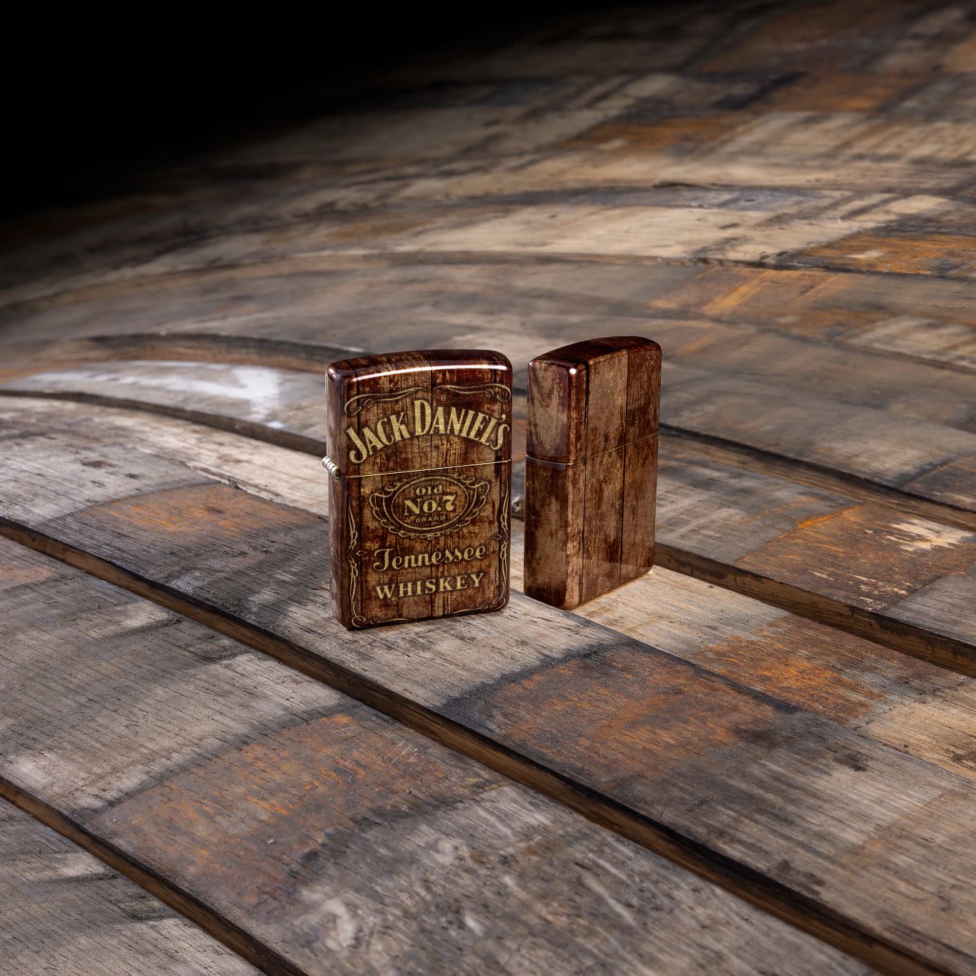 Lifestyle image of Zippo Jack Daniel's® Barrel Design 540 Tumbled Brass Windproof Lighter standing on a barrel.