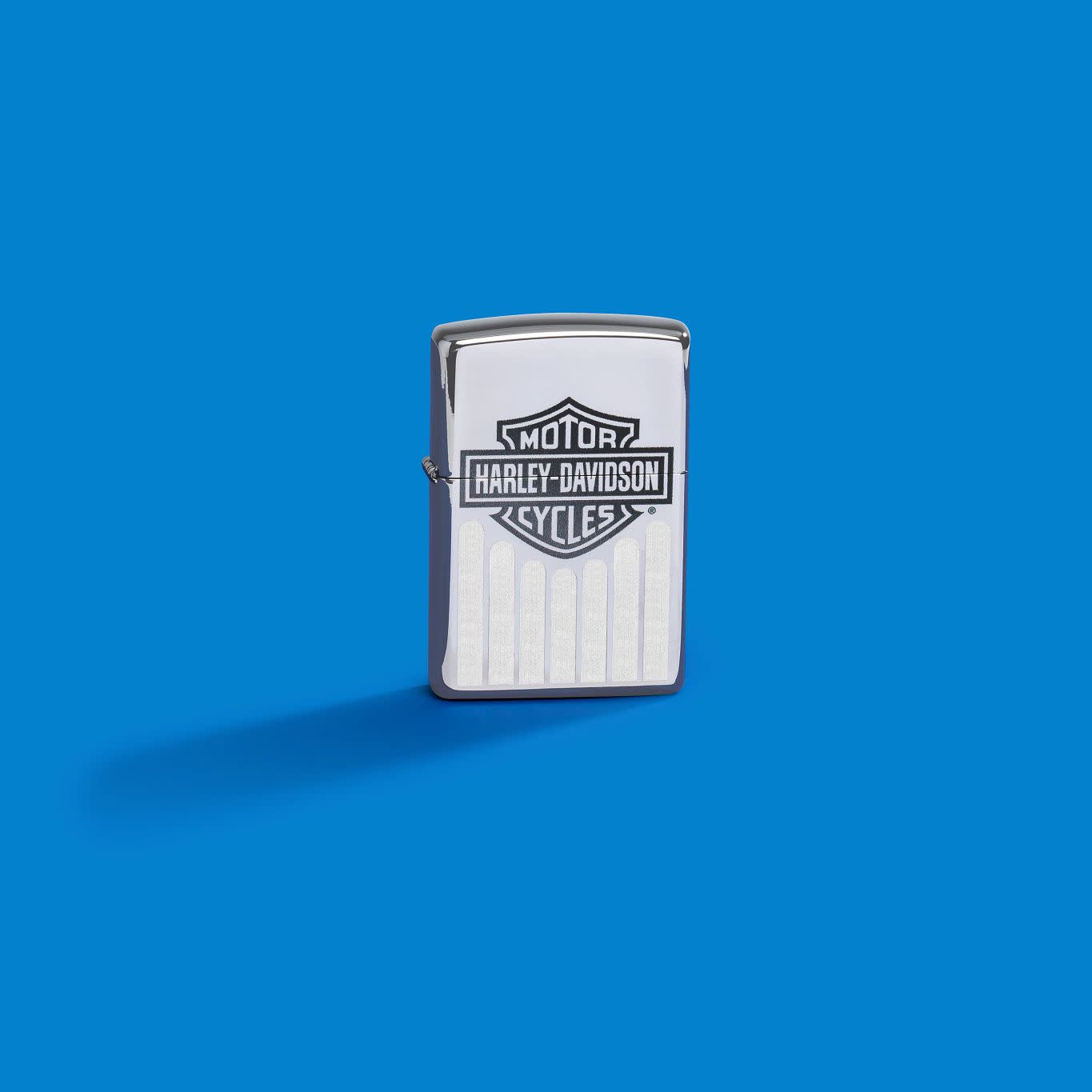 Lifestyle image of Zippo Harley-Davidson® High Polish Chrome Windproof Lighter on a blue background.