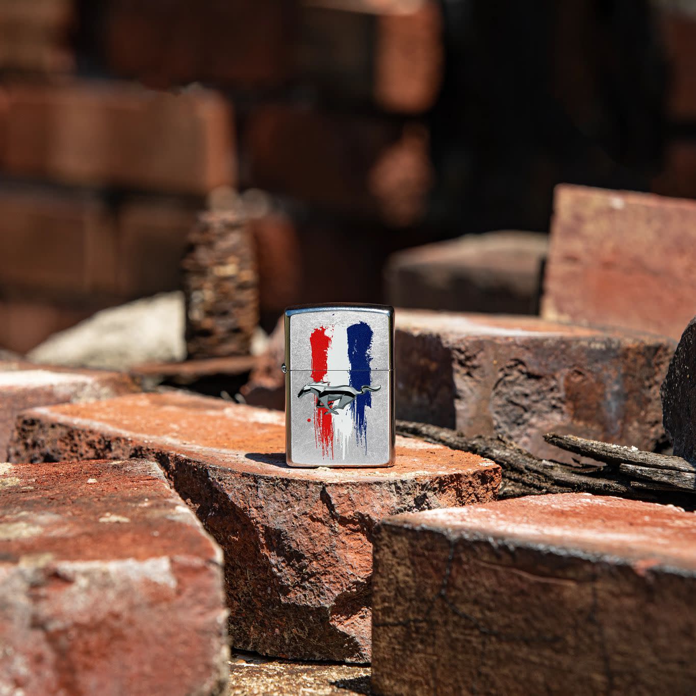 Lifestyle image of Zippo Ford Mustang Design Street Chrome Windproof Lighter standing on a loose brick with bricks surrounding.