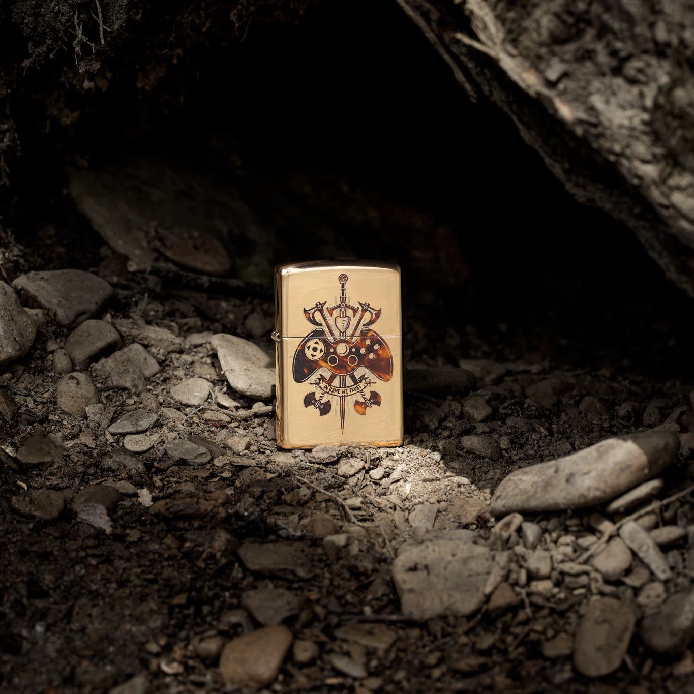 Lifestyle image of Zippo Gamer Creed Design High Polish Brass Windproof Lighter standing on rocks.