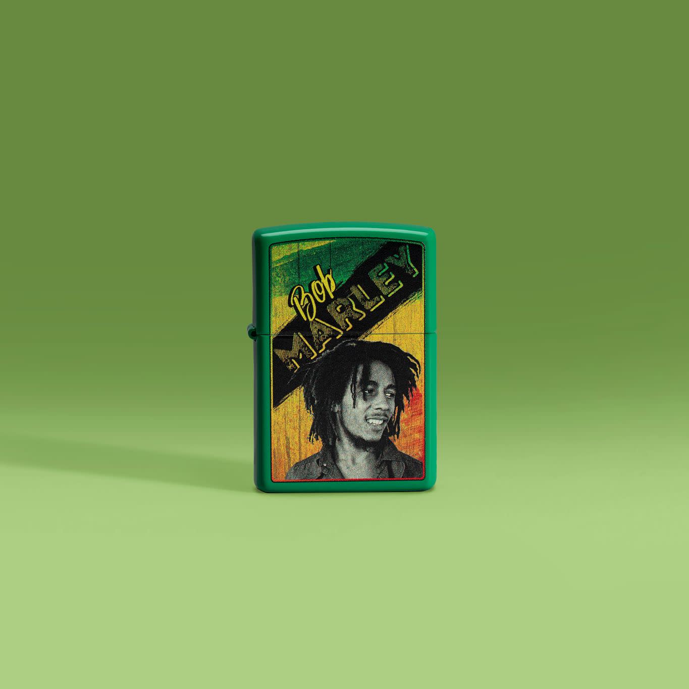 Lifestyle image of Zippo Bob Marley Grass Green Matte Windproof Lighter standing in front of a green background.