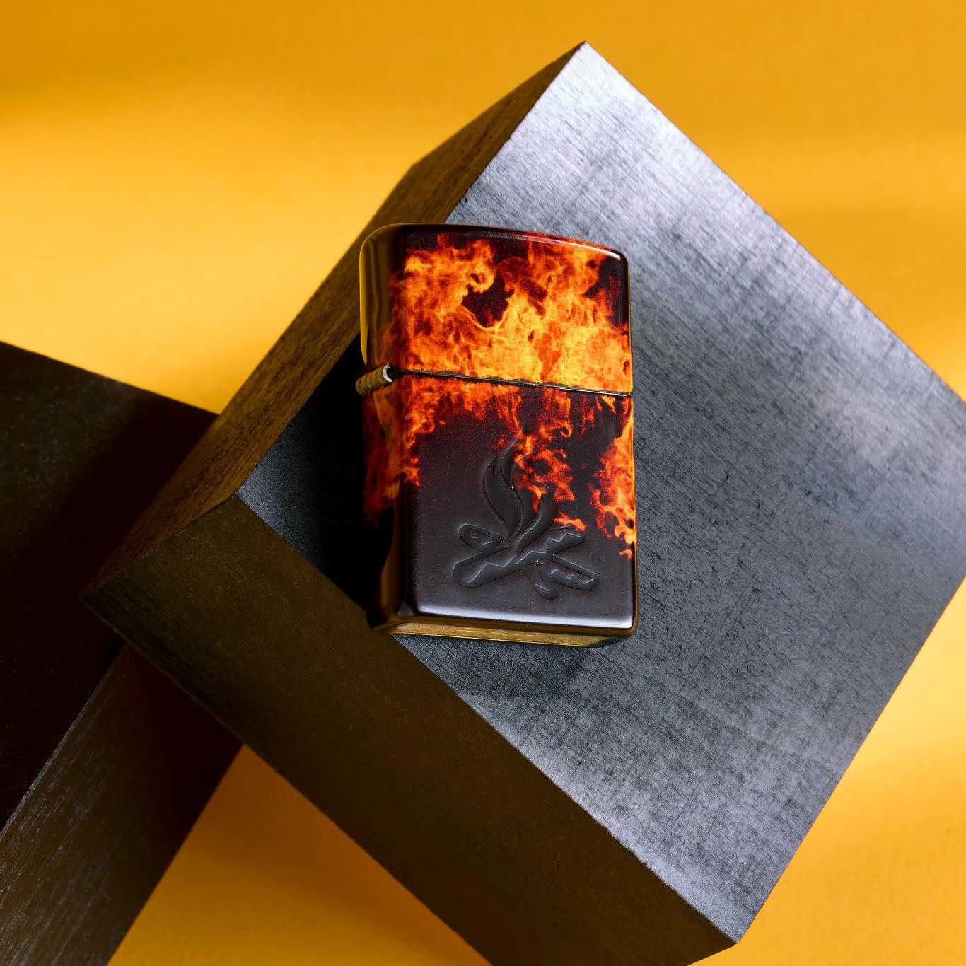 Lifestyle image of Zippo Fusion Inferno Design 540 Tumbled Brass Windproof Lighter on a metal cube with a light orange background.