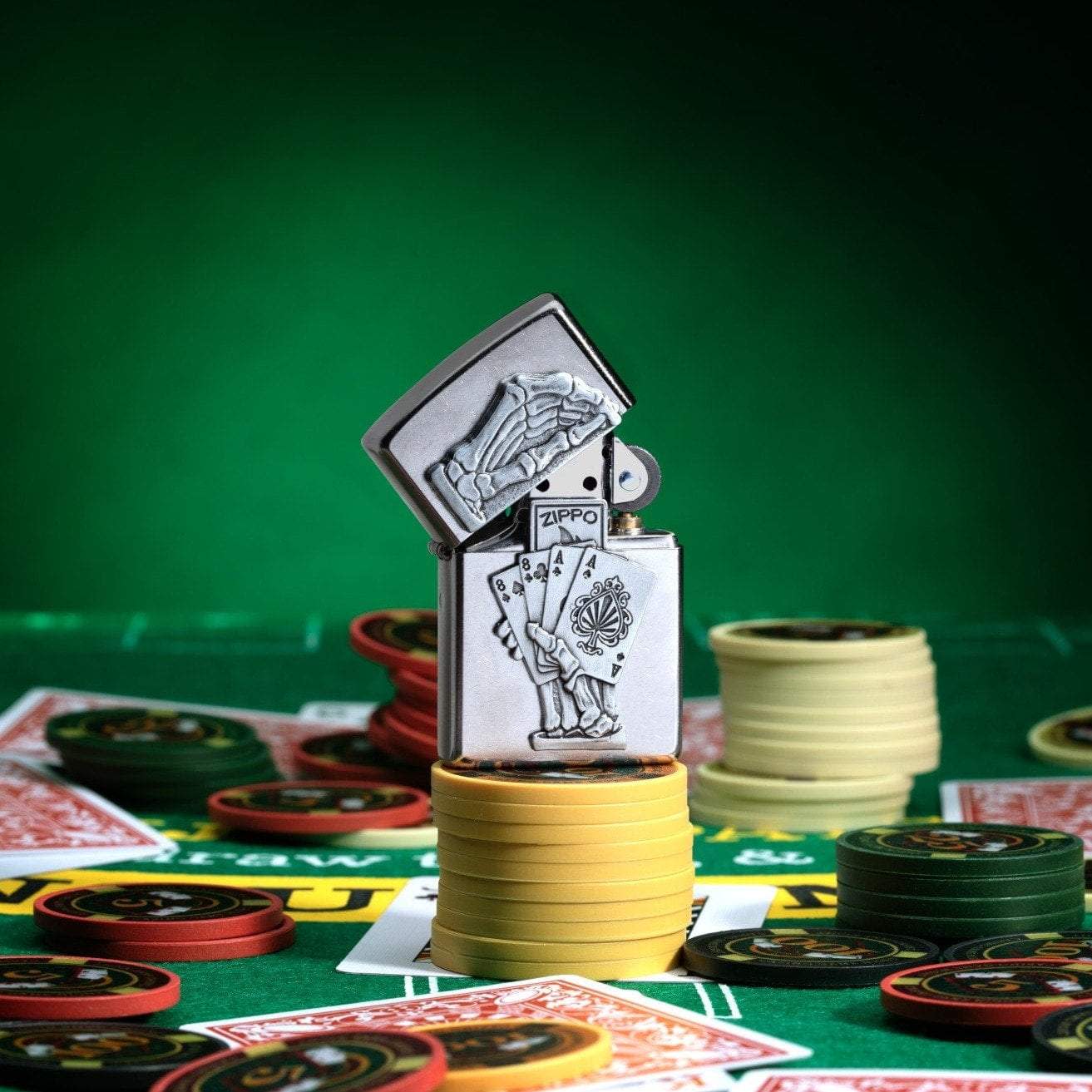 Dead Mans Hand Surprise Emblem Design Street Chromeâ„¢ Windproof Lighter standing on stacked poker chips, with cards and chips scattered all around a poker table.