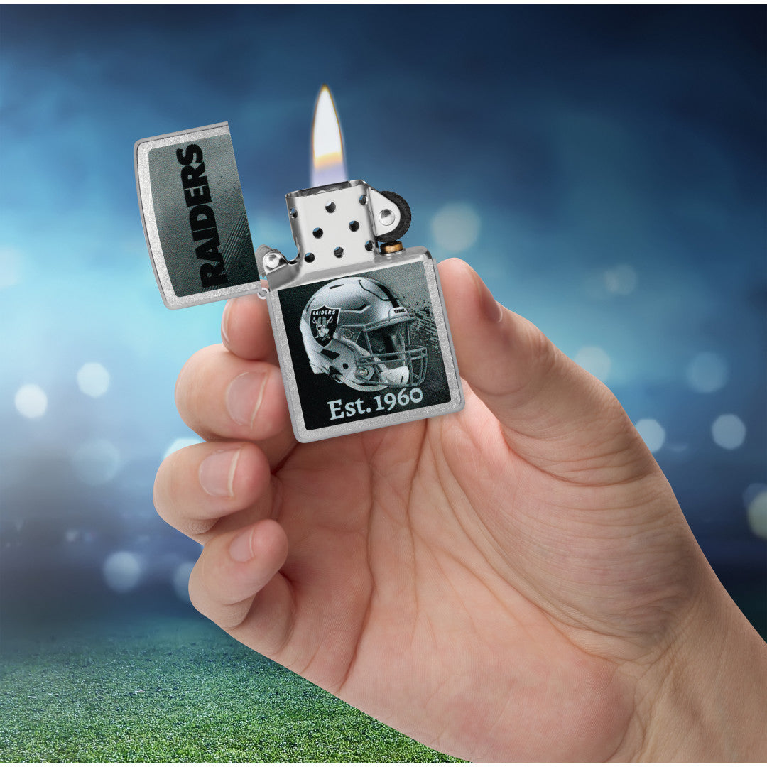 Zippo NFL Las Vegas Raiders Helmet Design Street Chrome Windproof Lighter lit in hand.