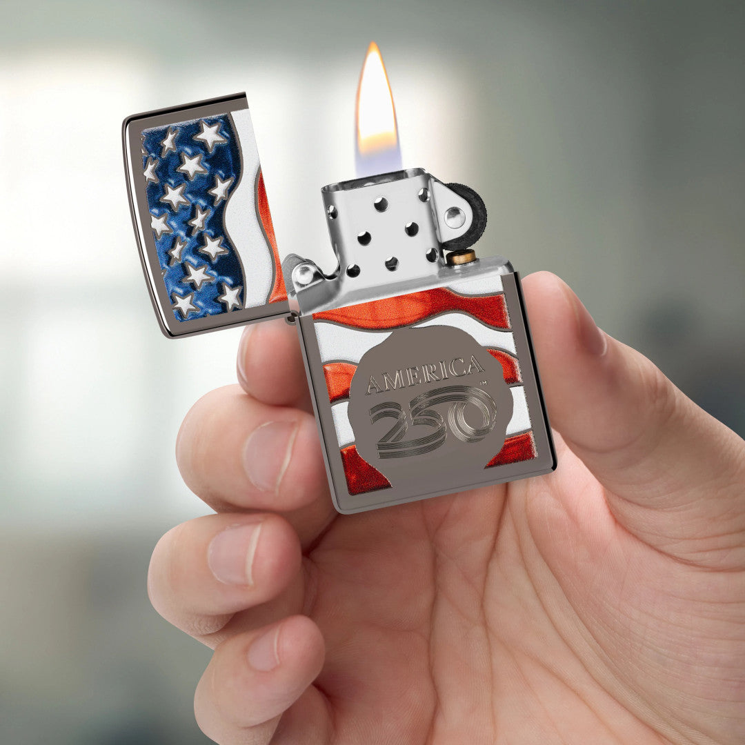 Zippo America250 Flag Design Black Ice Windproof Lighter lit in hand.