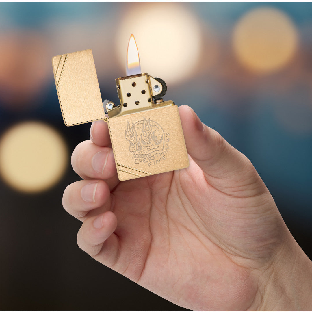 Zippo Everything's Fine Design Vintage Brushed Brass Windproof Lighter lit in hand.