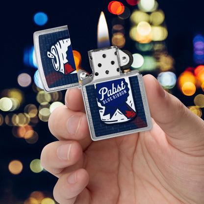 Zippo Pabst Blue Ribbon® Can Art Design Brushed Chrome Windproof Lighter lit in hand.