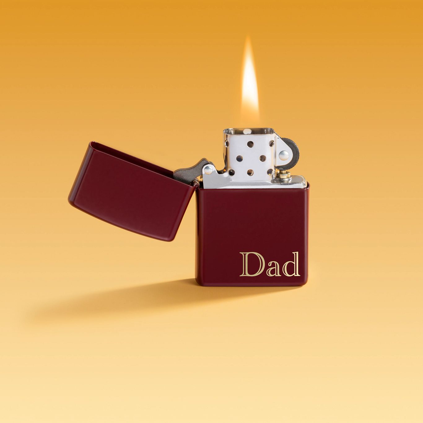 Lifestyle image of Zippo Dad Design SMS Windproof Pocket Lighter with its lid open and lit set against an ombre light orange to yellow background.