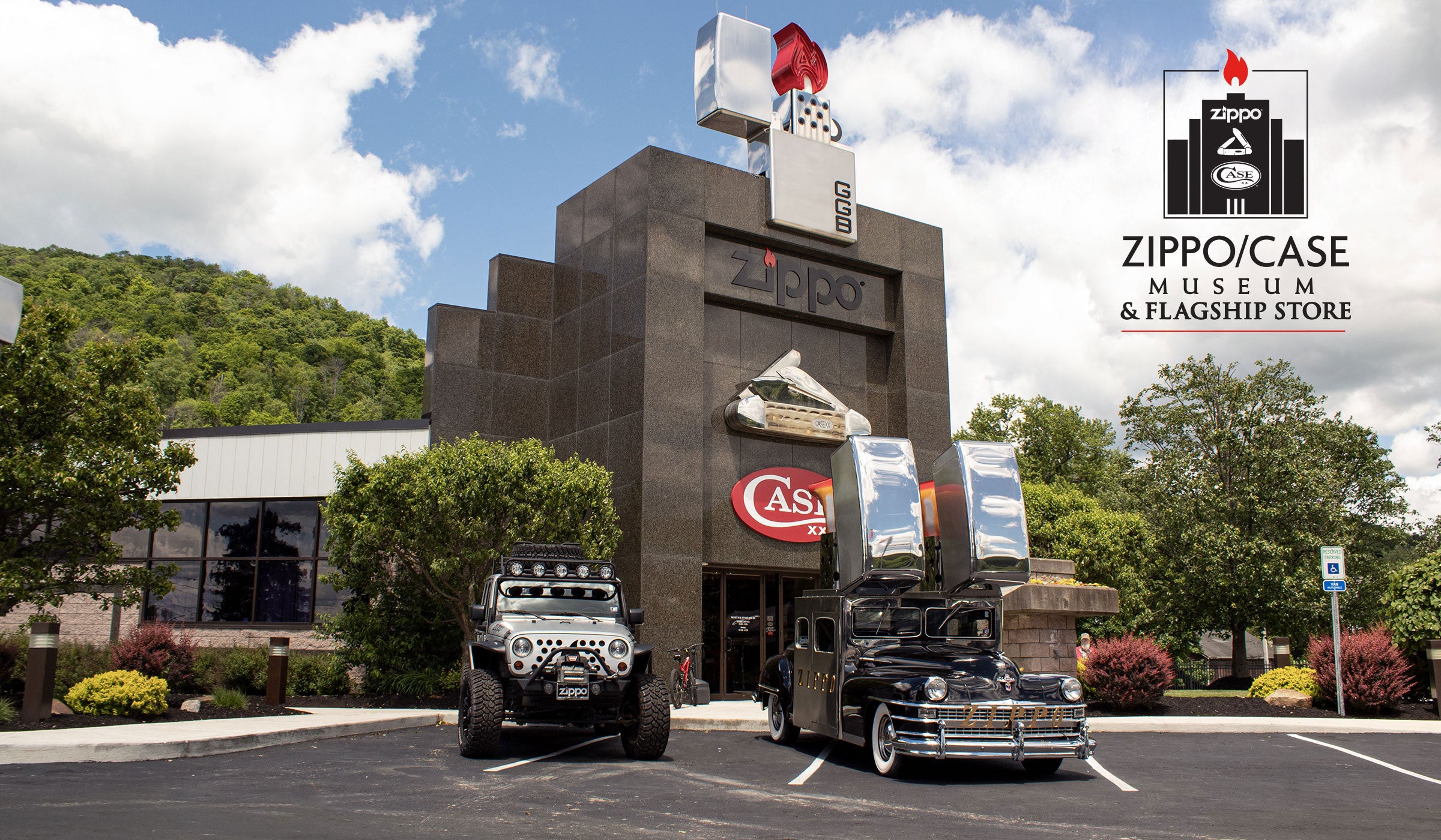 Zippo / Case Museum & Flagship Store building with two vehicles parked in front, trees, hills, and a cloudy sky. A large 'Zippo / Case Museum & Flagship Store' logo appears in the upper right.