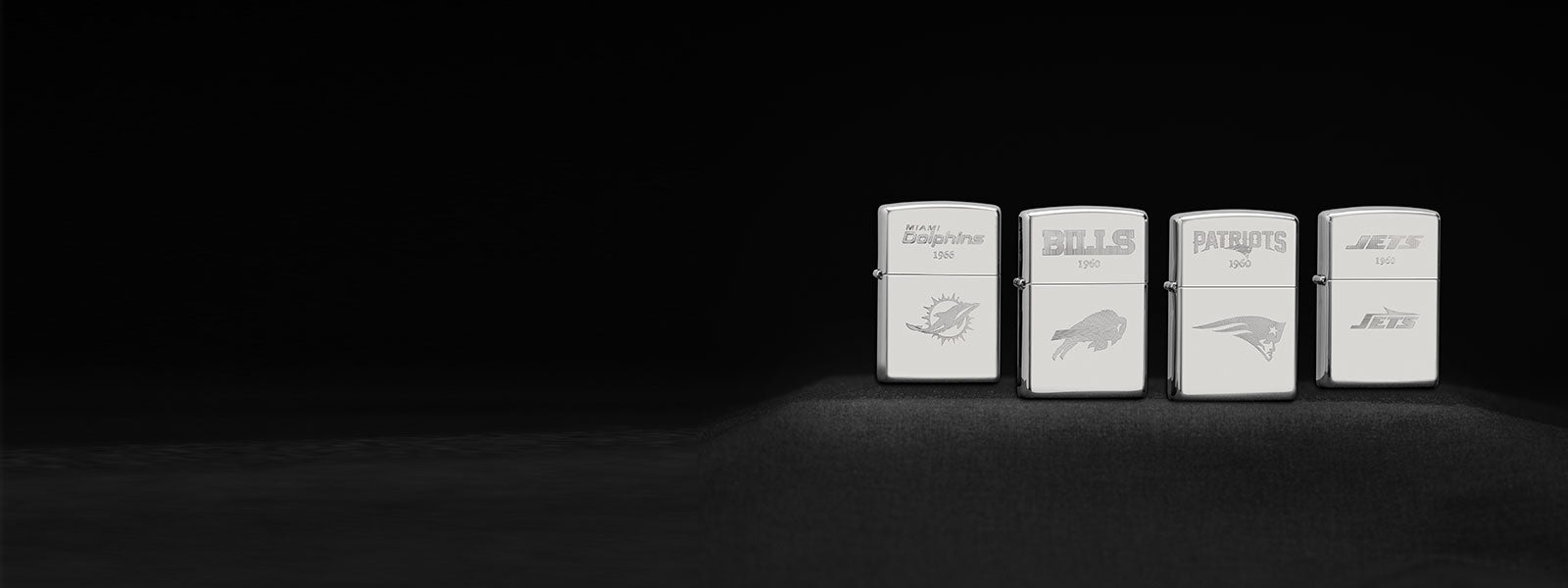 Four NFL Sterling Silver Zippo lighters with engraved designs on a black background