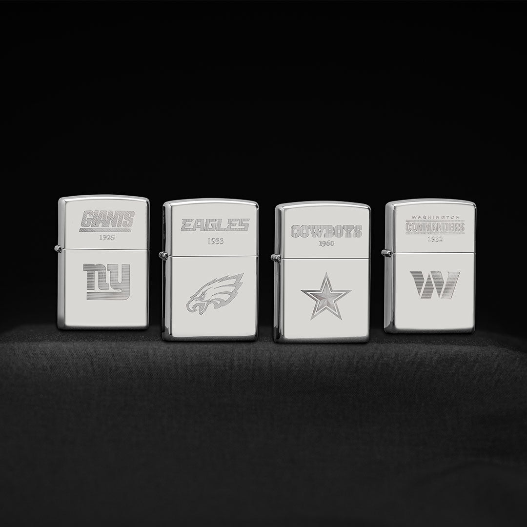 Four silver Zippo lighters with different logos on a black background