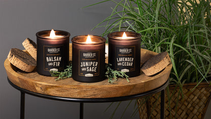 Lifestyle Image of Zippo Barber Street Candles on a wooden coffee table with plants, lit.