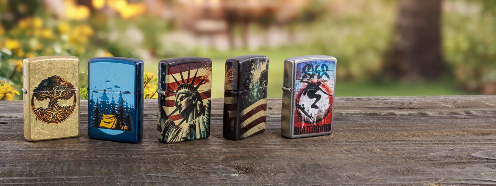 Five colorful Zippo lighters on a wood surface with trees in the background. 