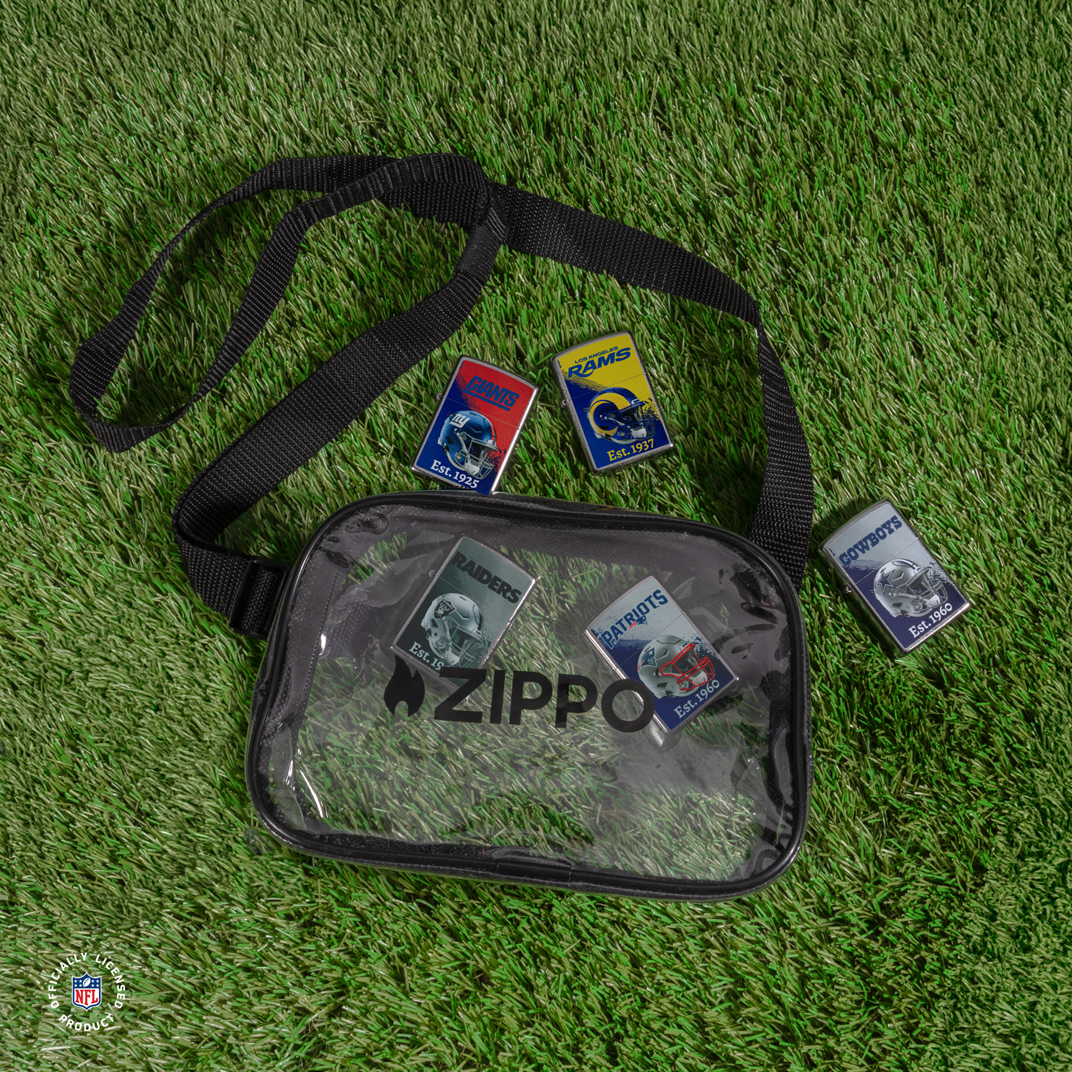 A clear Zippo bag with a black strap, laid flat on grass. The bag has ZIPPO printed on the front and contains five Zippo lighters around the bag.