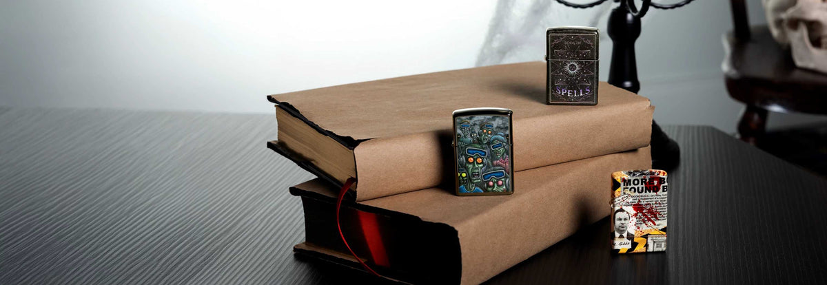 Three Zippo October Web Debut lightrs on a stack of books. 