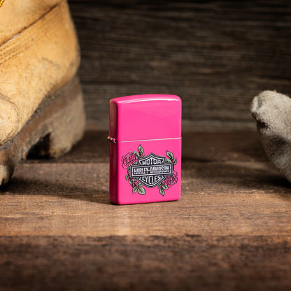 Lifestyle image of Zippo Harley-Davidson® Roses Frequency Windproof Lighter standing on a wooden floor with a work boot and glove sitting on either side.