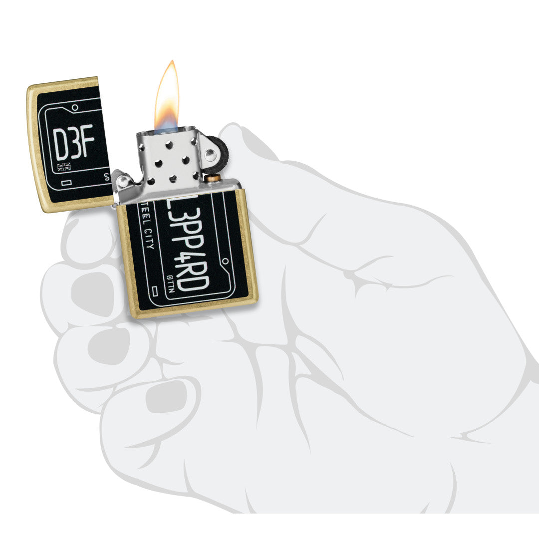 Zippo Def Leppard Steel City Design Street Brass Windproof Lighter lit in hand.
