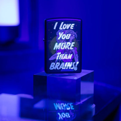 Lifestyle image of Zippo Black Light Brainiac Design Black Matte Windproof Lighter standing on a clear cube showing the front of the lighter glowing under a black light. 
