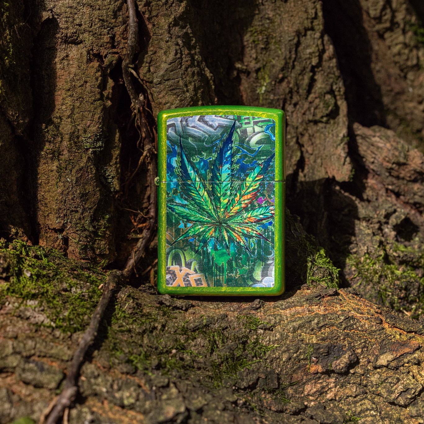 Lifestyle image of Zippo Graffiti Leaf Design Lurid Windproof Lighter standing against the base of a moss-kissed tree trunk.

