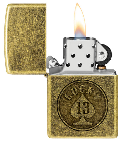 Zippo Lucky 13 Design Antique Brass Windproof Lighter with its lid open and lit.