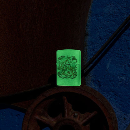 Lifestyle image of Zippo Def Leppard Glowing Hysteria Design Glow in the Dark Green Windproof Lighter standing on a rusty gear showing the front and non-hinge side of the lighter, while glowing in the dark.

