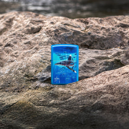Lifestyle image of Zippo Guy Harvey Co-Pilot Design Sky Blue Matte Windproof Lighter standing on a rocky surface showing the front of the lighter. 

