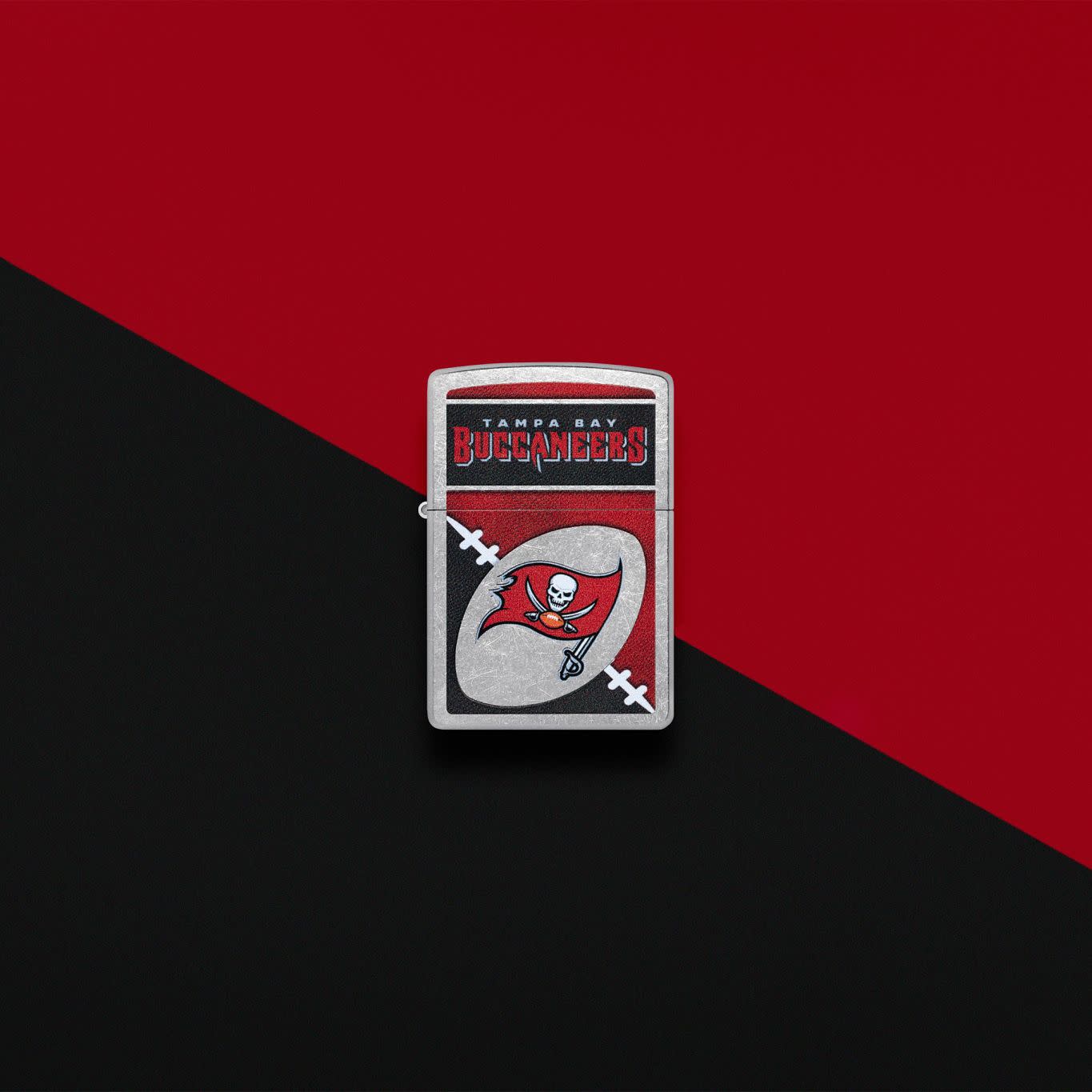 Lifestyle image of Zippo NFL Tampa Bay Buccaneers Street Chrome Windproof Lighter set on a black and red background.