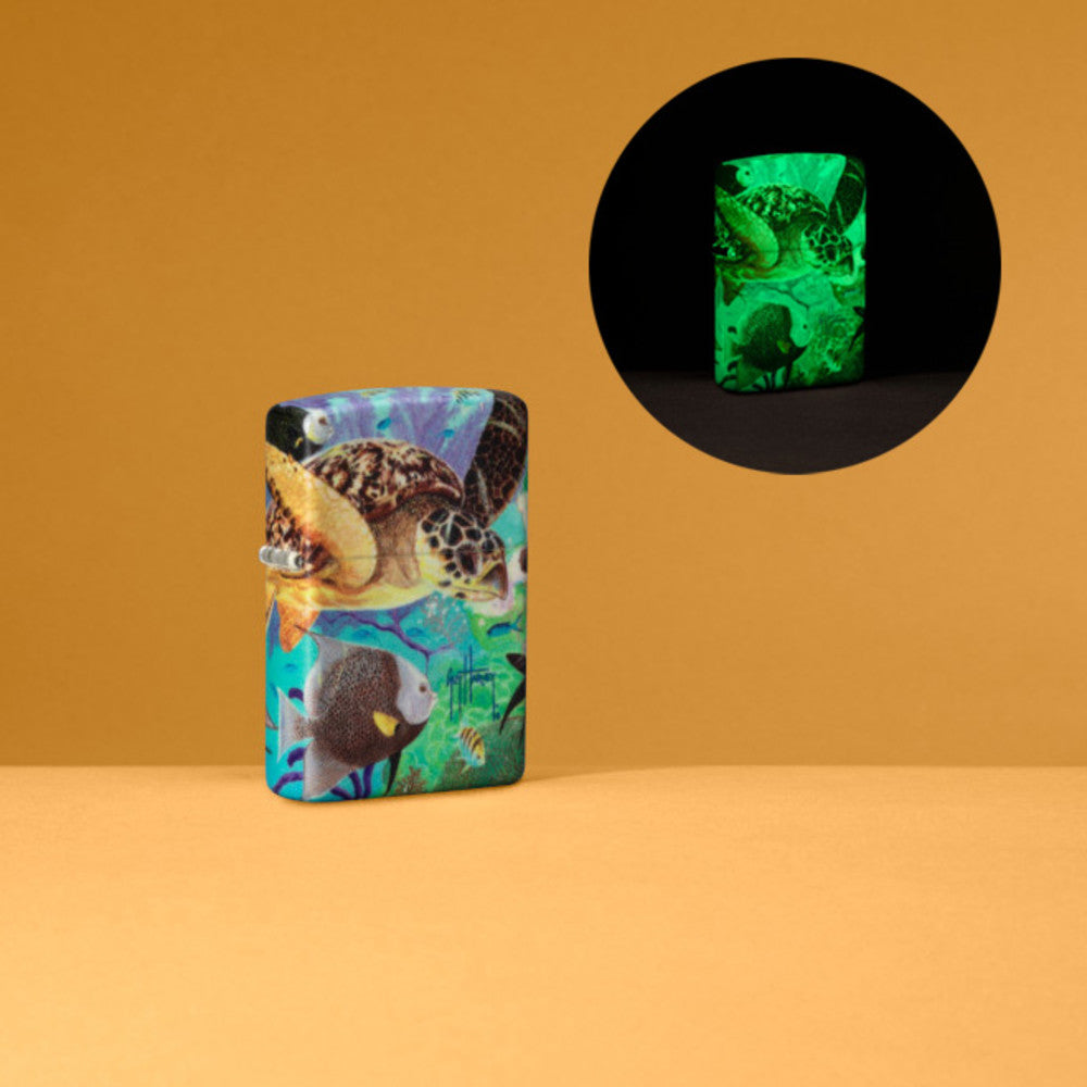 Lifestyle image of Guy Harvey Design Glow In The Dark 540 Color Windproof Lighter in an orange scene with an image of it glowing in the dark in the corner.