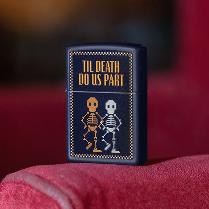 Lifestyle image of Zippo Til Death Do Us Part Design Navy Matte Windproof Lighter standing on the armrest of a red chair or sofa showing the front of the lighter. 

