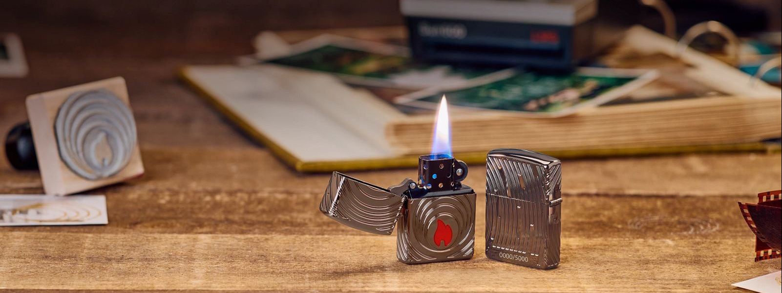 Zippo lighter on a wood surface with old photos in the background.