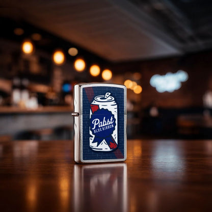 Lifestyle image of Zippo Pabst Blue Ribbon® Can Art Design Brushed Chrome Windproof Lighter standing showing the front of the lighter with an out of focus bar as the background. 

