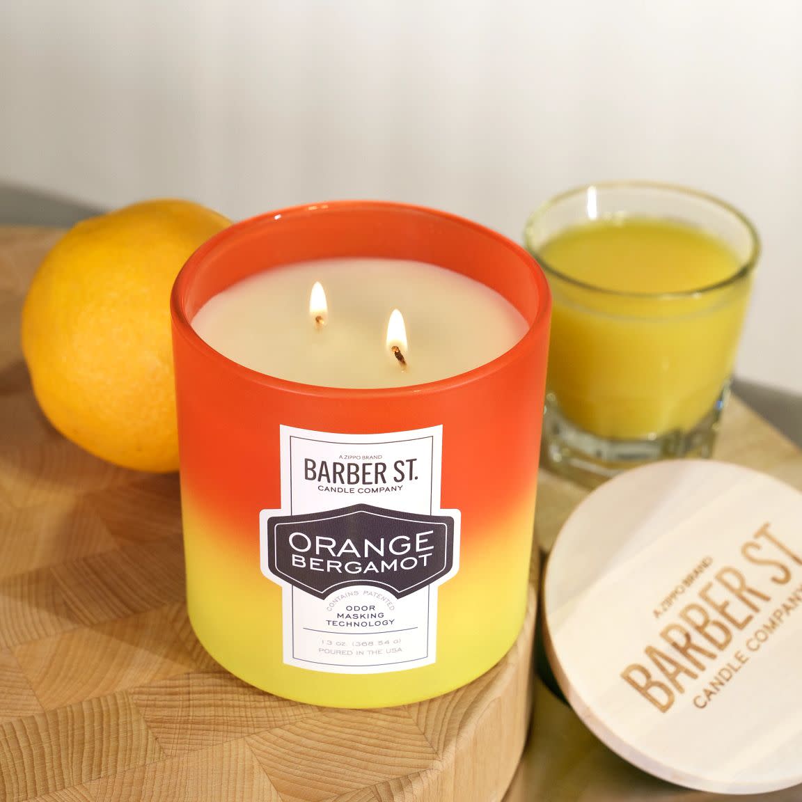 Lifestyle image of Zippo Barber Street Orange Bergamot Odor Masking Candle lit on a countertop.