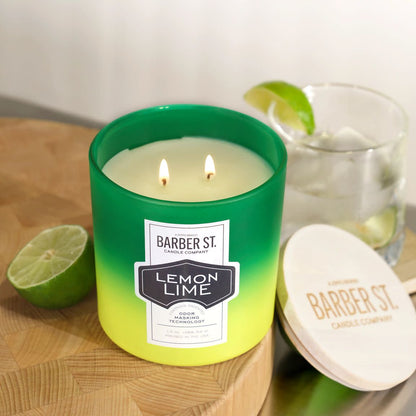 Lifestyle image of Zippo Barber Street Lemon Lime Odor Masking Candle lit on a countertop, standing with a drink and lime.