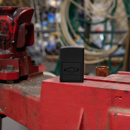 Lifestyle image of Zippo Chevrolet® Bowtie Design Black Matte Windproof Lighter in an auto shop setting.