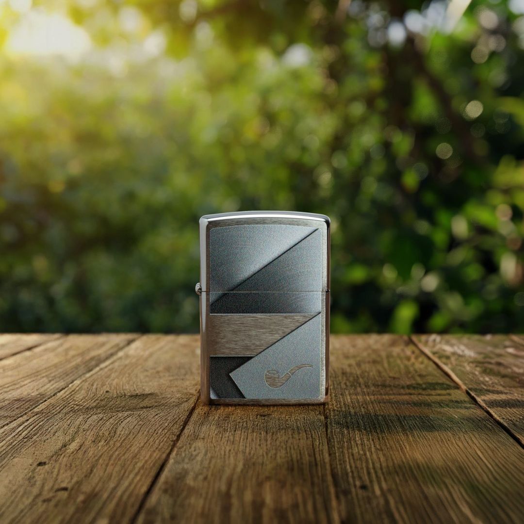 Lifestyle image of Zippo Metallic Design Pipe Lighter Brushed Chrome Windproof Lighter standing on a wooden deck showing the front of the lighter with an out of focus wooded area as the background. 

