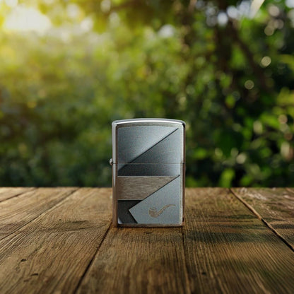 Lifestyle image of Zippo Metallic Design Pipe Lighter Brushed Chrome Windproof Lighter standing on a wooden deck showing the front of the lighter with an out of focus wooded area as the background. 

